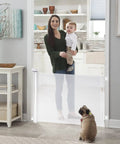 Mother holding child near Retractable Baby Gate For Stairs And Doors Indoor Outdoor Safety Gate Extends Up To 55 Inches Wide And 35 Inches High