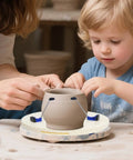 Child using 12 Inch Pottery Turntable Clamp For Ceramics, Adjustable 2 To 12 Inch Trimming Spinner, with adult assistance.