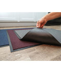 Person lifting corner of Ovation Entrance Mat 3 by 6 Blue for Home or Office Heavy Duty Tufted Decalon Pile on floor