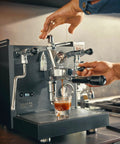 User extracting espresso from the Alto Dual Boiler Espresso Machine With PID Control And Flow Adjustment For Top Shelf Precision Shots With Built In Timer And Pro Steam Paddle In Sleek Stainless Finish.
