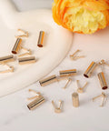 Gold Alloy Shoelace Tips 10 Pack With Cylindrical Aglets And V Shaped Grippers End Caps scattered on a white surface