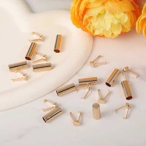 Gold Alloy Shoelace Tips 10 Pack With Cylindrical Aglets And V Shaped Grippers End Caps scattered on a white surface