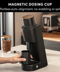 Rock Solid Single Dose Coffee Grinder With Brawny 38 Mm Conical Burrs And Butter Smooth Stepless Dial For Bold Espresso Pour Over Pulls Low Retention Anti Static Frame In Matte Black with magnetic dosing cup in use.