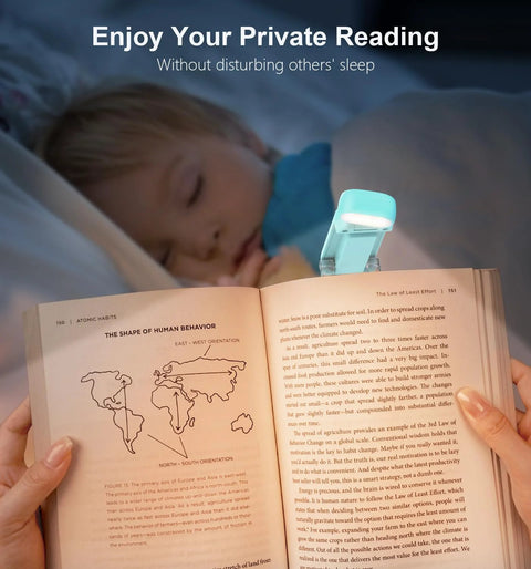 Blue clip-on Gritin rechargeable reading light attached to an open book on a bed.