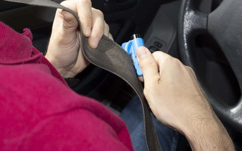 Close-up of blue resqme emergency car escape tool used to cut a seatbelt in a car