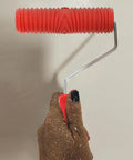 Red Grain Pattern Paint Roller For Wall Texturing With Ergonomic Plastic Handle held in hand against a wall surface.