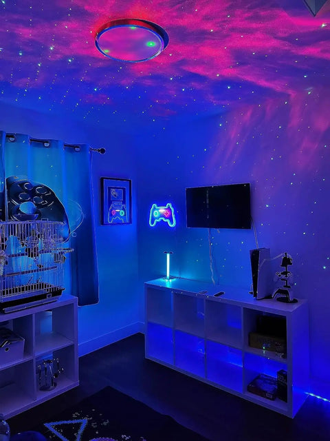 Lit night room with Galaxy Star Projector With Bluetooth Speaker displaying nebula cloud on ceiling, LED decor, and gaming setup.