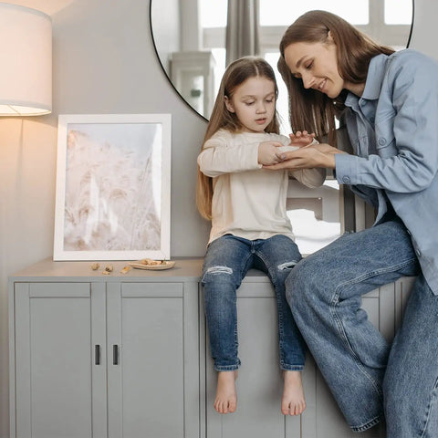 Mother and daughter sitting on gray cabinet, minimalistic modern decor