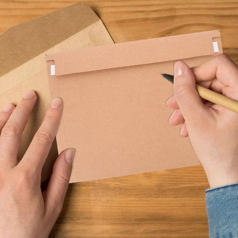 A4 Self Sealing Kraft Brown Envelopes Pack Of 30 Thickened Flat Cardboard Mailers being handwritten on a wooden table