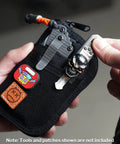Close-up of black EDC Pouch With Ten Compartments Small Pocket Tool Organizer held in hand, decorated with patches and multitools.