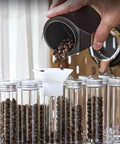 Pouring coffee beans into clear glass canisters of the 14 Piece Single Dose Coffee Bean Storage Tubes With Airtight One Way Valve.