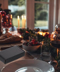 15 Pack Black Corrugated Paper Shipping Boxes for storage and moving, visible near a candlelit dining table.