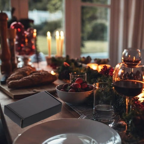 15 Pack Black Corrugated Paper Shipping Boxes for storage and moving, visible near a candlelit dining table.