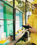 Beekeeper in yellow suit checking tablets near beehives using 8 Pack Bee Water Feeders For Beehives, Beekeeping Watering Station