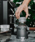 Using 53mm Gravity Adaptive Espresso Distributor for 54mm Portafilters in Breville Bottomless setup, stainless steel tool on countertop