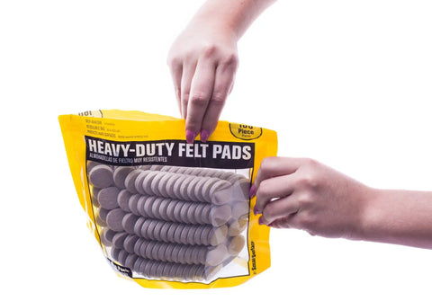 Person holding Heavy Duty Self Adhesive 1-Inch Round Tan Furniture Felt Pads 160-Piece Value Pack In Resealable Bag