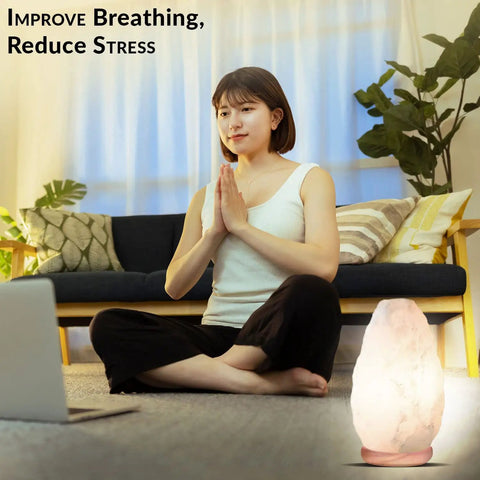 Woman meditating with Crystal Salt Lamp Night Light on neem wood stand, living room setting, calm ambience.