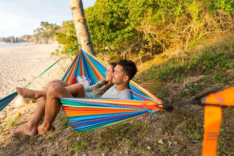 Double Deluxe Camping Hammock For Two 11 ft long with 500 lb capacity, showing colorful stripes and easy setup by the beach.