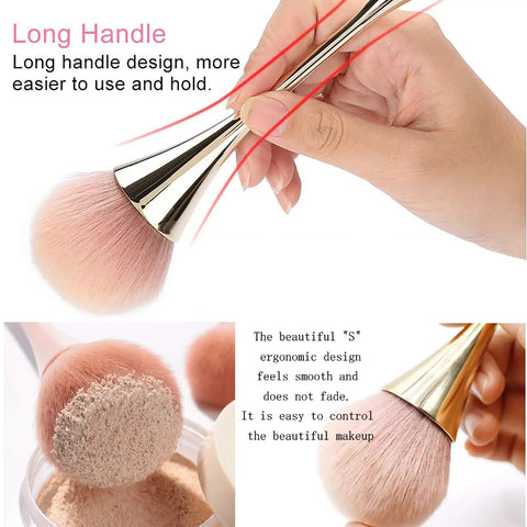 Hand holding large nail dust brush cleaner, long gold handle with pink nylon bristles. 2 Pack Nail Dust Brush Cleaners For Acrylic Dip Powder Makeup And Blush Large Manicure Cleanup Tools For Salon And Home Use Nail Art Gold And Black Kit.