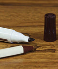 Close-up of marker and wax stick from 13 Piece Wood Repair Kit with Markers and Wax Sticks for Scratches and Stains on wood surface.
