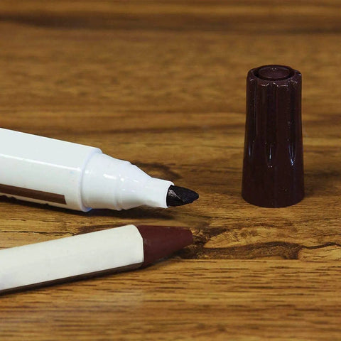 Close-up of marker and wax stick from 13 Piece Wood Repair Kit with Markers and Wax Sticks for Scratches and Stains on wood surface.