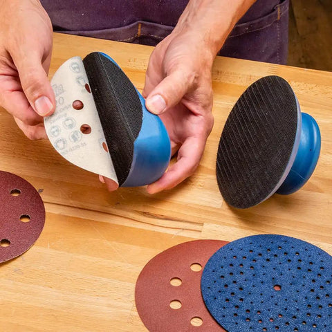 Hands holding 2 Piece Sanding Block Set For 5 Inch Hook And Loop Discs Durable And Versatile For Softening Edges Detail Sanding And Getting More Life Out Of Your Abrasives On Any Orbital Sander with discs