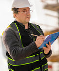 Top Shelf Seven Pocket Mesh Safety Vest In Matte Black For Active Crews Featuring Fly Airflow Polyester worn by a man writing notes.