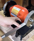 Heavy Duty Woodturning And Carving Tool Sharpening Jig For 6 Inch To 8 Inch Bench Grinders with a hand guiding a tool on the grinder.