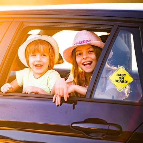 Children smiling from car window with Baby On Board Car Sign Pack, Two Window Stickers With Super Strong Double Suction Cups installed on window.