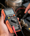 Hands using Digital Multimeter 6000 Count TRMS Auto Ranging For DC AC Voltage And Current Resistance Capacitance Testing on engine