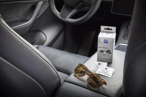 ZEISS Lens Wipes box with two sachets and tortoiseshell sunglasses on a car center console.