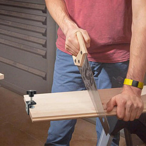 Man woodworking with a saw, using a Set Of 4 Heavy Duty C Clamps For Woodworking And Metalworking, black aluminum alloy clamp on a wooden board.