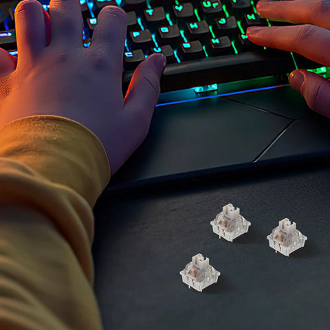 Ten Piece Set Of Linear Actuators For Mechanical Gaming Keyboards on desk with hands typing, showcasing grey parts.
