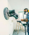 Person using a sander with Dust Free Pro Grade 25 Pack 9 Inch Mesh Sanding Discs Set With 60 80 120 180 240 Grits for drywall finishing