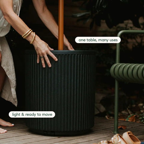 Person adjusting durable outdoor umbrella side table with umbrella hole for patio next to deck chair