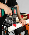 Front view of Bi-Metal Hole Saw Kit in use; cordless drill cuts white PVC pipe with red hole saw.