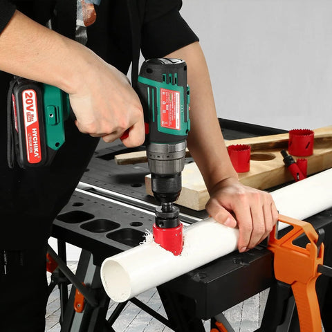 Front view of Bi-Metal Hole Saw Kit in use; cordless drill cuts white PVC pipe with red hole saw.
