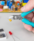 Close-up of Four And A Quarter Inch Magic Diagonal Small Head Cutter cutting a wire with PCB components, blue and silver finish, Swiss made.