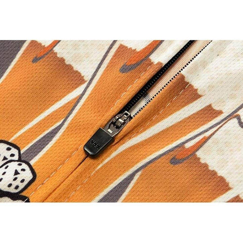 Close-up of orange and black zipper detail on fabric with dice pattern.