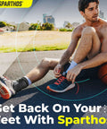 Man wearing Lace Up Ankle Brace With Adjustable Support For Running And Court Sports Like Basketball And Volleyball Go-To Injury Recovery Gear For Sprains And Stability, Compression Stabilizer Ankle Brace For Men And Women Gray Large, sitting on a basketball court