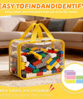 Clear PVC bag with colorful toy blocks, yellow handles, zippers, and labels on a carpet, titled Eight Piece Extra Large Colorful Toy Storage Bags With Zippers And Labels Clear PVC Waterproof Organizers For Board Games Puzzle Pieces Building Blocks And Handmade Accessories.