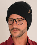 Person wearing Unisex Cuffed Beanie Thick Double Knit Winter Skull Cap Black Cozy Warm For Skiing Running And Daily Cold Weather Protection