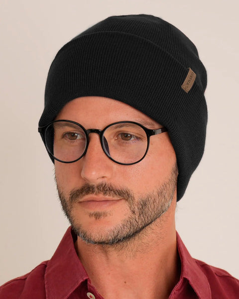 Person wearing Unisex Cuffed Beanie Thick Double Knit Winter Skull Cap Black Cozy Warm For Skiing Running And Daily Cold Weather Protection