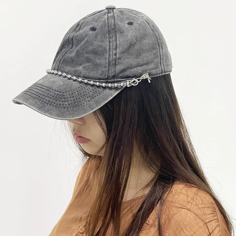 Woman wearing a mesh baseball cap with detachable pearl hat chain, featuring metal beads and lobster claw clasp, side view
