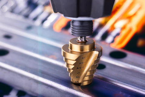 Close-up of Titanium Nitride Coated HSS Step Drill Bit with One Quarter Inch Hex Shank Ten Imperial Step Sizes in use on metal.