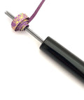 Close-up of handmade paper bead roller for quilling, stainless steel tip with 1/8 inch diameter and wooden handle, paper strip inserted.