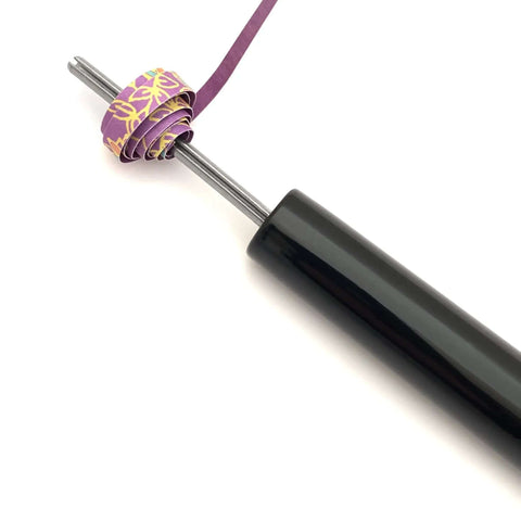 Close-up of handmade paper bead roller for quilling, stainless steel tip with 1/8 inch diameter and wooden handle, paper strip inserted.