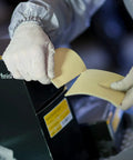 Person using Soft Hand Sanding Sheets 4.5 By 5 Inch Grit 240 On Perforated Roll from box, wearing gloves, close-up