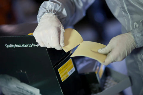 Person using Soft Hand Sanding Sheets 4.5 By 5 Inch Grit 240 On Perforated Roll from box, wearing gloves, close-up