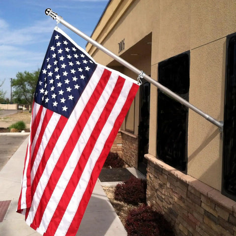 Top Notch 1.5 Inch Flag Pole Rings With Anti Wrap Swivel Clips And 360 Degree Rotating Aluminum Alloy Mounting Hardware For Rad Tangle Free Flag Flying With Rust Resistant Carabiners Two Pack holding an American flag in outdoor setting.